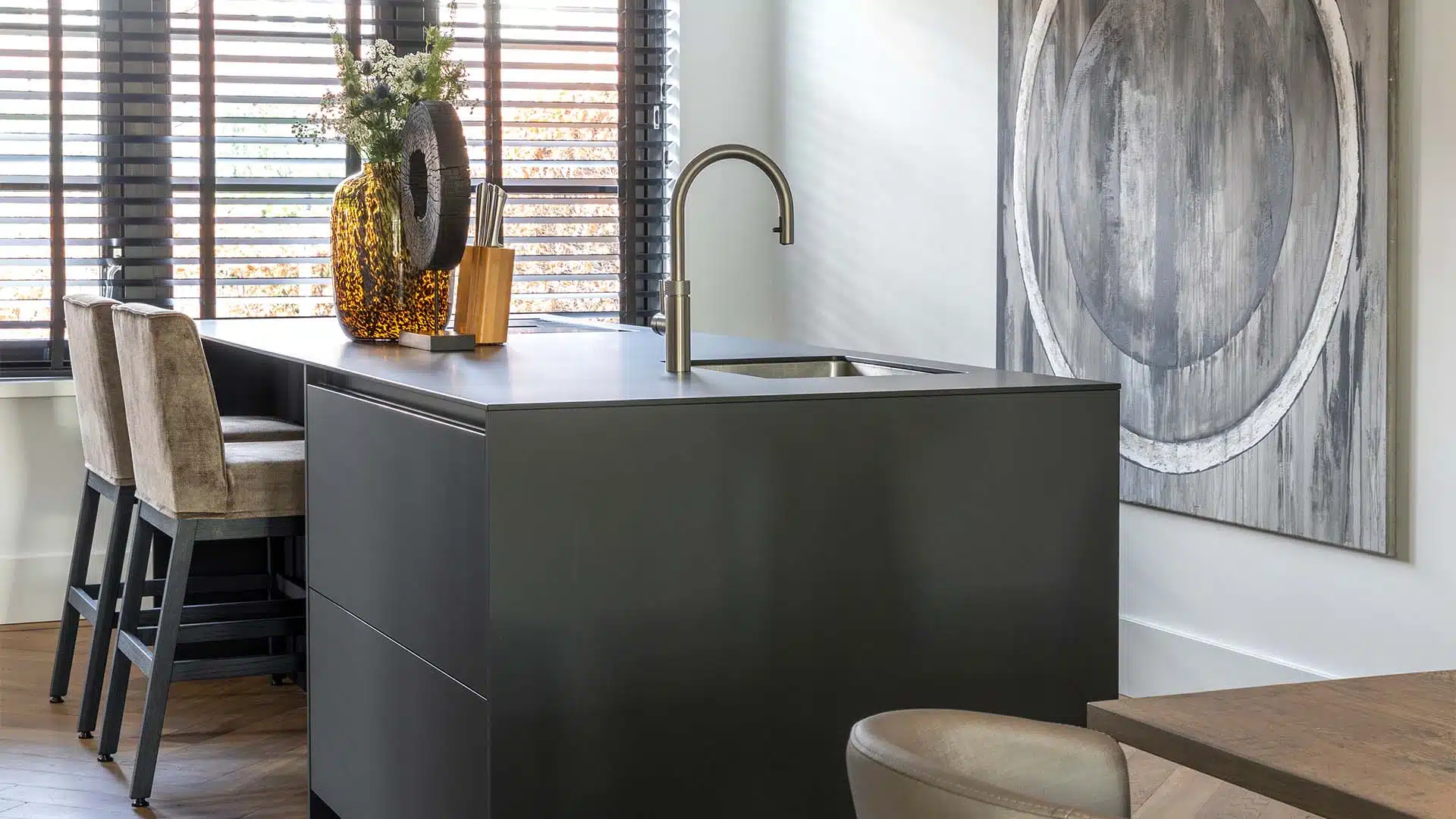 minimalistische zwarte keuken met bar, beige stoelen, quooker kraan en details